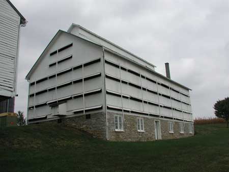 This barn is banked, with stripping room on the basement level and facing south. It is located near the main barn, corn barn (just visible at left), and house.
