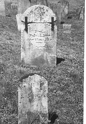 broken headstone supported by metal straps