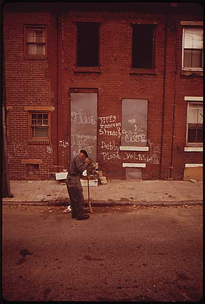 Image of man sweeping the street in front of rowhomes. Photo courtesy of the U.S. National Archives