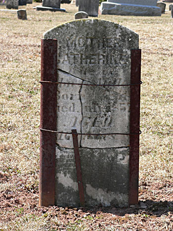 broken headstone supported by metal straps